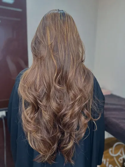 A gorgeous honey blonde balayage on long, flowing hair. The curls at the end add a touch of glamour and volume.