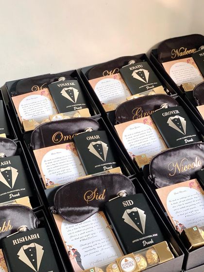 A full view of the customized groomsmen hampers, each with a personalized eye mask and hip flask. The black and gold theme is always a classic and sophisticated choice.