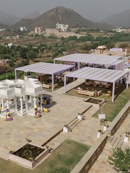 A drone's eye view of the entire Haldi setup, showing the mandap, guest seating, and the breathtaking mountain landscape of Udaipur.