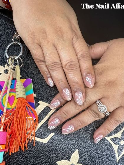 A similar botanical design with white leafy vines on a sheer nude base. This elegant and understated art is perfect for a sophisticated look.