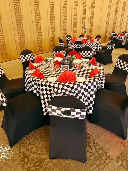 The dining tables were dressed in checkered-flag tablecloths with black chair covers and bright red napkins, creating a bold, graphic look for the monochromatic Cars party.
