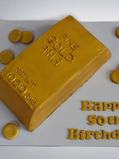This solid gold bar cake was made for a 50th birthday celebration. The entire bar is a non-fondant chocolate cake, airbrushed with edible gold paint to create a realistic and luxurious finish.