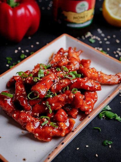 Indulge in the perfect balance of sweet and spicy with our Crispy Honey Chilli Chicken. This saucy delight is a guaranteed hit at any party.
