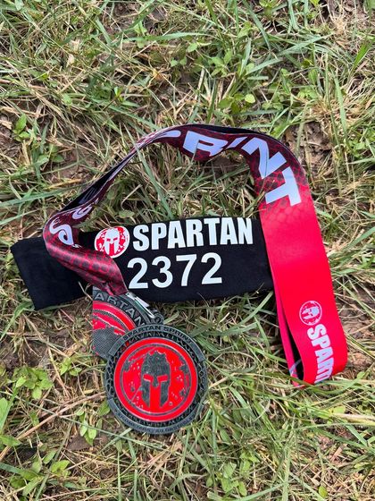 The reward for all the grit and sweat. A close up of the Spartan Race finisher medal and headband. A tangible reminder of the challenge you overcame.