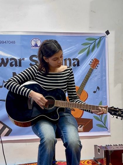 A teen guitarist demonstrates her skills during the Guru Purnima celebration. We focus on building strong fundamentals that allow students to tackle any song they love.
