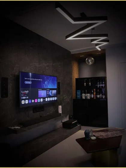 A beautifully finished living area with a wall-mounted TV, in-wall speakers, and custom ceiling lighting. This is an example of how our technical solutions blend perfectly with high-end interior design.