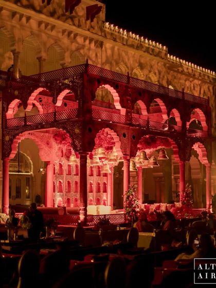 The 'Kaanch Bagh' mandap illuminated in a dramatic red light against the palace backdrop. This design was created to honor the rich traditions of the venue while creating a mesmerizing, palatial vibe for the evening.