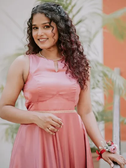 A beautiful shot of a bridesmaid in her pink dress. The makeup is soft and romantic, with a focus on enhancing her natural curls and radiant skin.