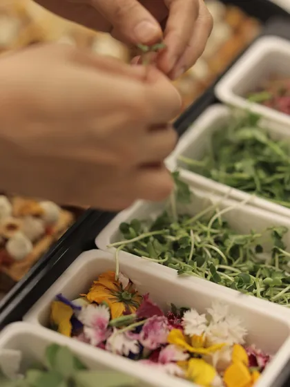 Behind the scenes, our team prepares hors d'oeuvres using fresh herbs and edible flowers, a testament to our commitment to quality.
