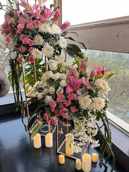 We love playing with height and dimension in our floral designs. This arrangement uses tiered stands to display beautiful bouquets of pink lilies and white chrysanthemums, surrounded by the warm glow of LED candles.