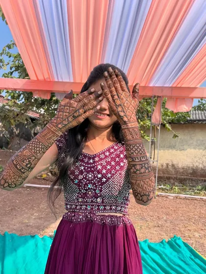 A happy bride and former student showing off her intricate back-hand mehendi design. The geometric patterns and detailed work extend up the entire forearm.