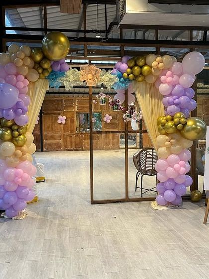 A beautiful pastel balloon archway creating a grand entrance for a first birthday party at a restaurant.