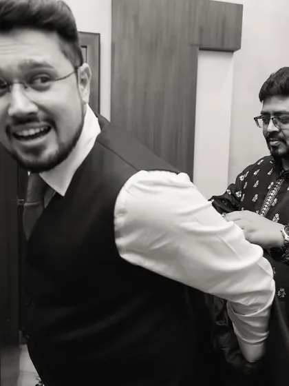 A fun, candid black and white shot of the groom getting help with his suit.