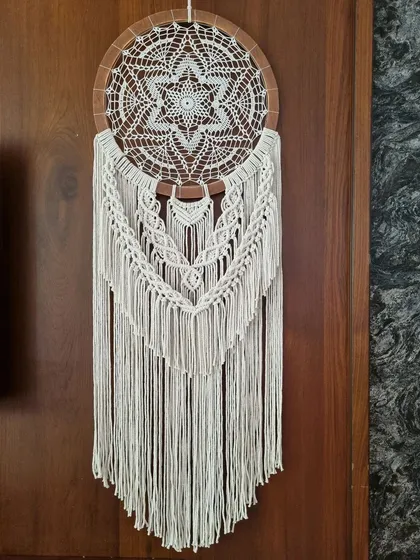Crafted with intricate knots and a beautiful crochet centerpiece, this macrame wall hanging is a masterpiece of timeless elegance. It's designed to invite serenity and grace into any space.