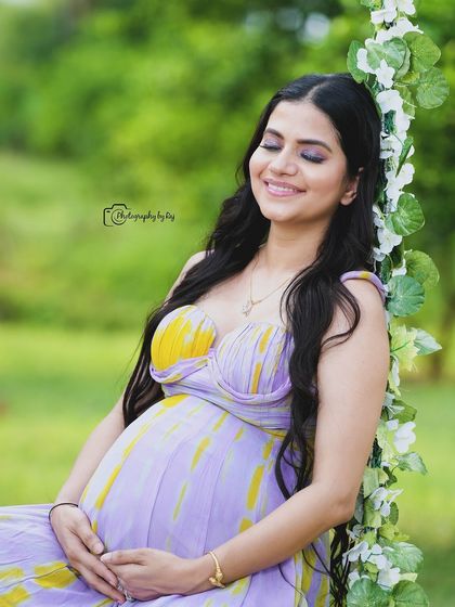 The pure bliss of motherhood. This close-up shot captures a serene smile as she cradles her bump, wearing a lovely lavender and yellow sundress.