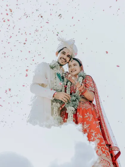 An artistic low-angle shot of the couple surrounded by smoke and petals, creating a dreamy, ethereal feel as if they are floating on a cloud.