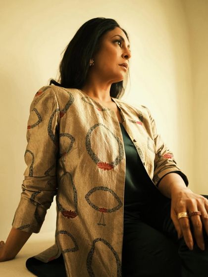 A seated portrait that feels like a painting, with soft lighting highlighting the texture of the jacket.