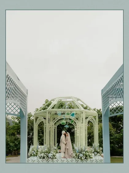 A wide shot of the wedding ceremony in Dehradun. The beautiful pastel-colored gazebo and the stunning mountain backdrop create a picturesque and serene setting for the couple's vows.