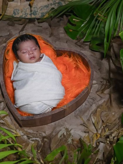 Happy Ugadi! This newborn is nestled in a heart-shaped basket within a lush green setup, symbolizing new beginnings and the beauty of nature during the festival.