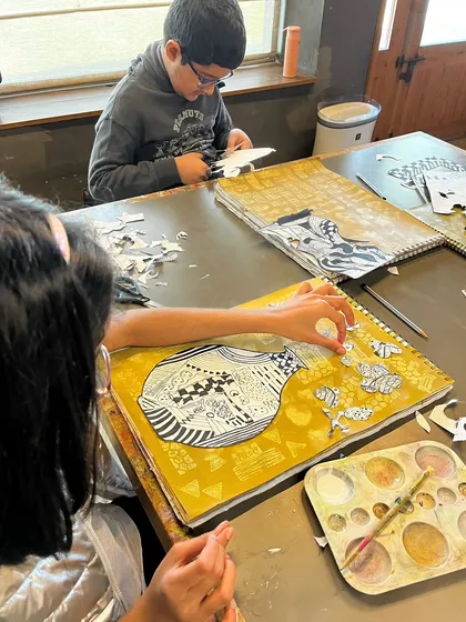 Students work on their still life collages, carefully placing their patterned cut-outs to create a balanced composition.