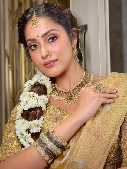 A tribute to the golden grace of a South Indian bride. This look features shimmering gold tones on the eyes, flawless skin, and traditional details that come together to create a look of pure, radiant elegance.