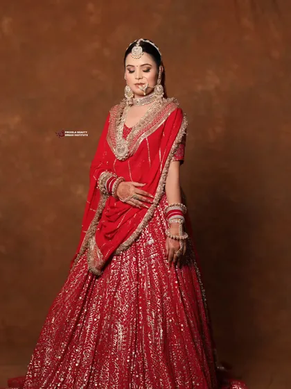 A stunning bride in a shimmering red lehenga. This look is perfect for a grand evening reception, with makeup that glows under the lights.