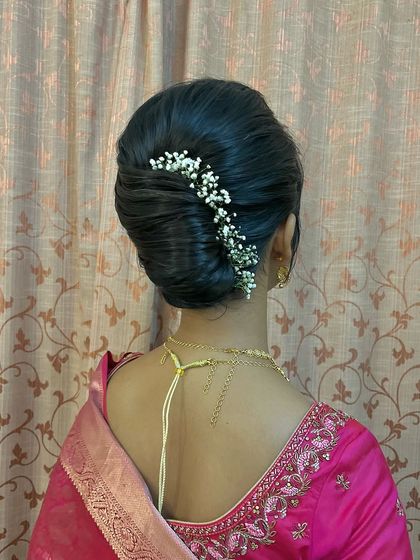 A sleek French twist style bun with a line of baby's breath, combining classic technique with a modern touch.