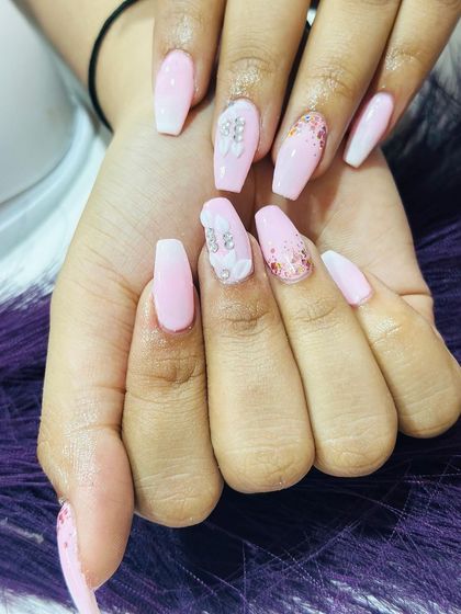 A soft and pretty pink set on coffin nails. The design is elevated with intricate 3D flowers and scattered glitter accents.