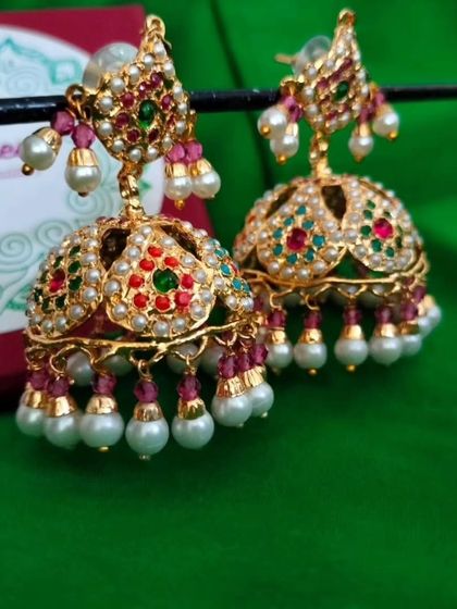 A product shot of the restocked 'दामिनी' (Damini) earrings. These multi-coloured jhumkas are incredibly versatile and can be paired with many different outfits.