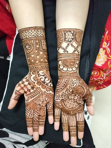 A classic and elegant party henna design. The patterns are very neat and structured, with bands of detail on the wrist and intricate work on the palm and fingers.