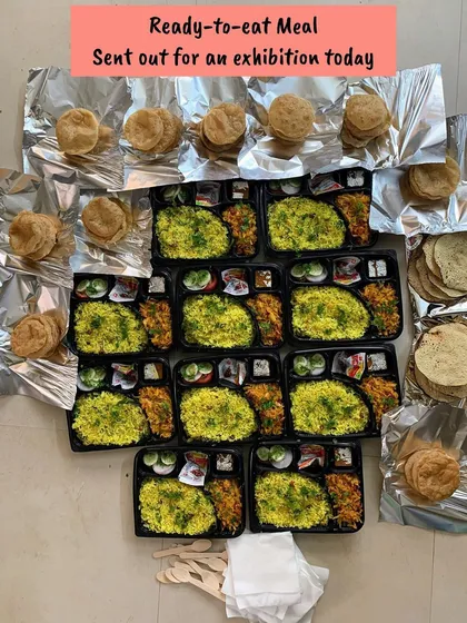 An overhead view of the ready-to-eat meals prepared for an exhibition, with puris and papads packed separately.
