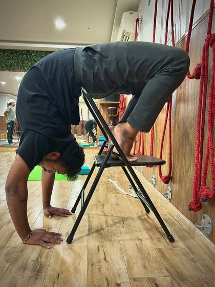 This student demonstrates how to use the chair to lift into a backbend from the hands. It's a challenging pose that builds significant upper body and core strength.