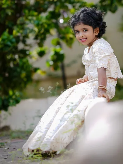 For the little ones, I create custom ethnic wear that is both beautiful and comfortable. This is a custom-stitched white lehenga with a scalloped hem and matching top, perfect for festivals and family functions.