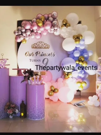 A princess-style decoration with a lavender and pink color scheme. The custom backdrop and glittery purple pedestals give it a very royal and elegant feel.