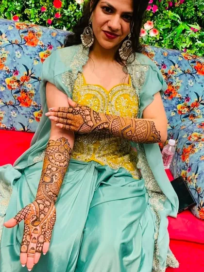 A happy client displaying her beautiful peacock-themed mehndi that covers her full arm.
