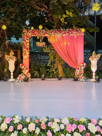 A vibrant and floral stage setup perfect for a sangeet or engagement party. The combination of pink drapes and lush flowers creates a celebratory atmosphere.