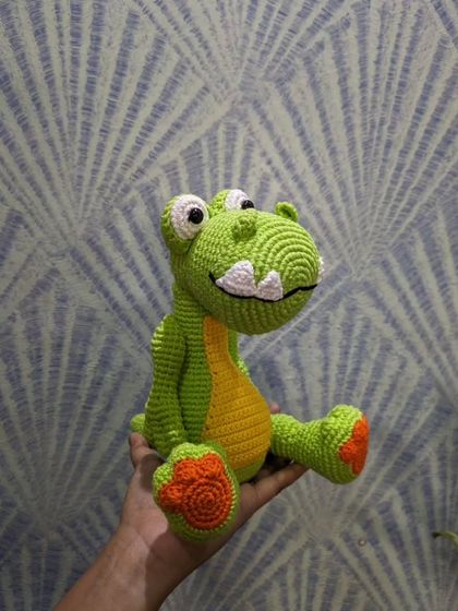 Holding the green dinosaur toy to show his size and friendly character.