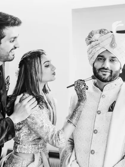 The groom's sister giving him a final touch-up. This black and white photo is full of sibling love and laughter.
