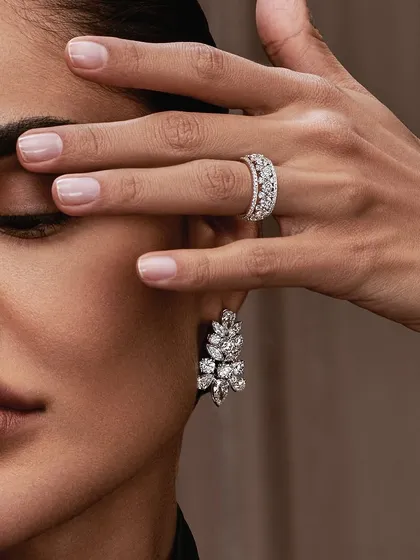 Another close-up beauty shot from the Aukera campaign. The makeup is clean and understated with a focus on flawless skin texture, allowing the intricate design of the earrings and ring to capture attention.