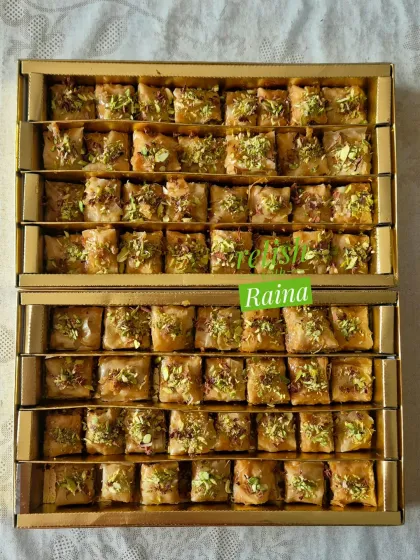 A brightly lit shot of two boxes of Baklava, showing the glistening syrup and the vibrant green of the pistachio topping.