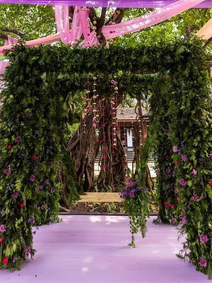 A lush, green mandap or entrance arch, made entirely of foliage and accented with delicate hanging flowers, perfect for an eco-chic or garden wedding.