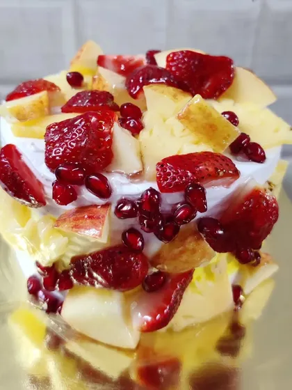 For a lighter and fresher option, I offer this fresh fruit cake. It's generously topped with seasonal fruits like chopped strawberries, pomegranate seeds, and apple slices over a light cream frosting.