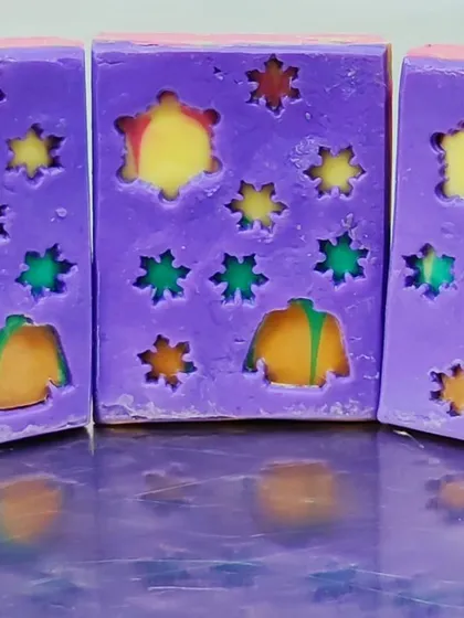 A winter-themed peekaboo soap. The colorful soap underneath looks like cozy sweaters and stars against a purple night sky.