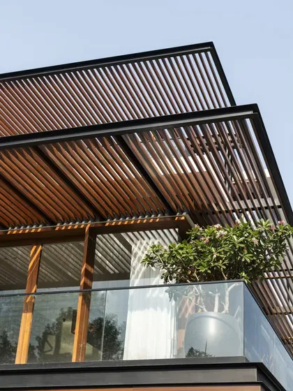 A detail of the layered pergolas, crafted from steel and timber. This element is key to the home's transformation, providing shade while adding a strong graphic and textural quality to the facade.