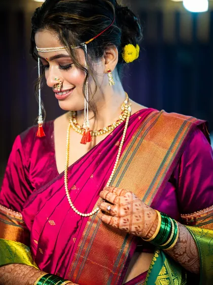 A quiet, happy moment. The soft makeup look, with its warm tones and gentle smile, captures the beautiful essence of a traditional Maharashtrian bride.