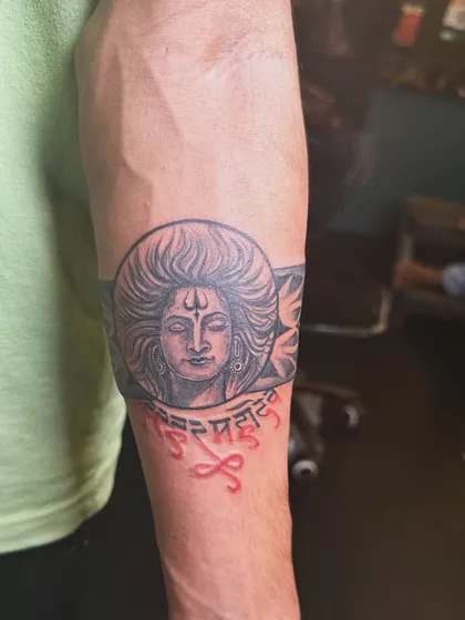 A different angle of the Shiva armband tattoo, showing the intricate details of his hair and the tribal patterns on the band. The combination of portrait and pattern work makes it unique.