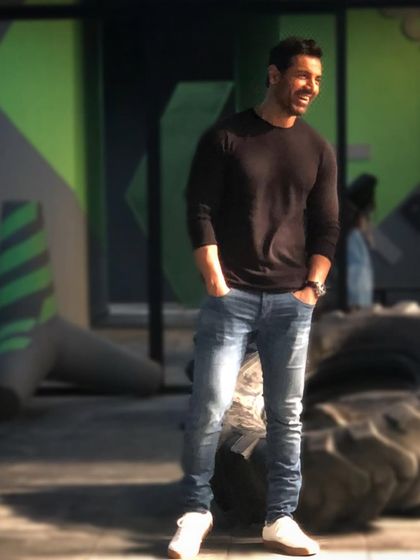 A candid shot of John Abraham on set. This effortless look with a black sweater and jeans is a perfect example of his signature style.