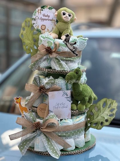 A closer look at the jungle-themed diaper cake. It's a practical and adorable gift, featuring a plush monkey, a little dinosaur, and a personalized card, all crafted with care.