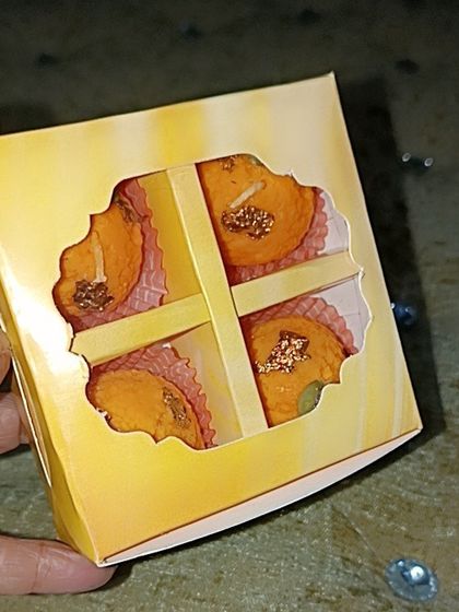 A hand holding the 4-cavity yellow box, showing its compact and giftable size.