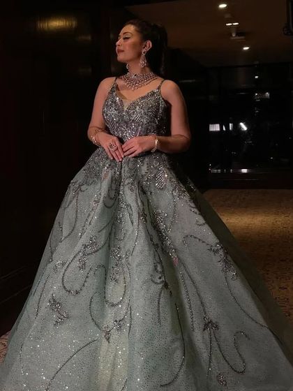 A client posing in the grey-green ball gown, showing its full silhouette and how it catches the light.